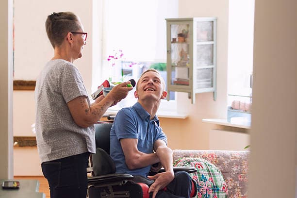 Carer assisting a person in a wheelchair with daily living support